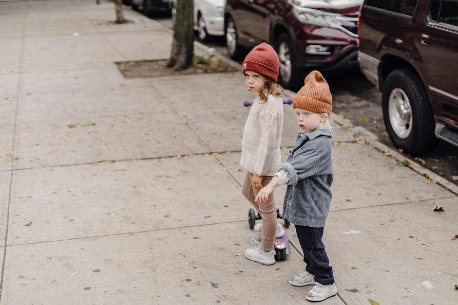 Two children with scooters enjoying a carefree day in an urban neighborhood.